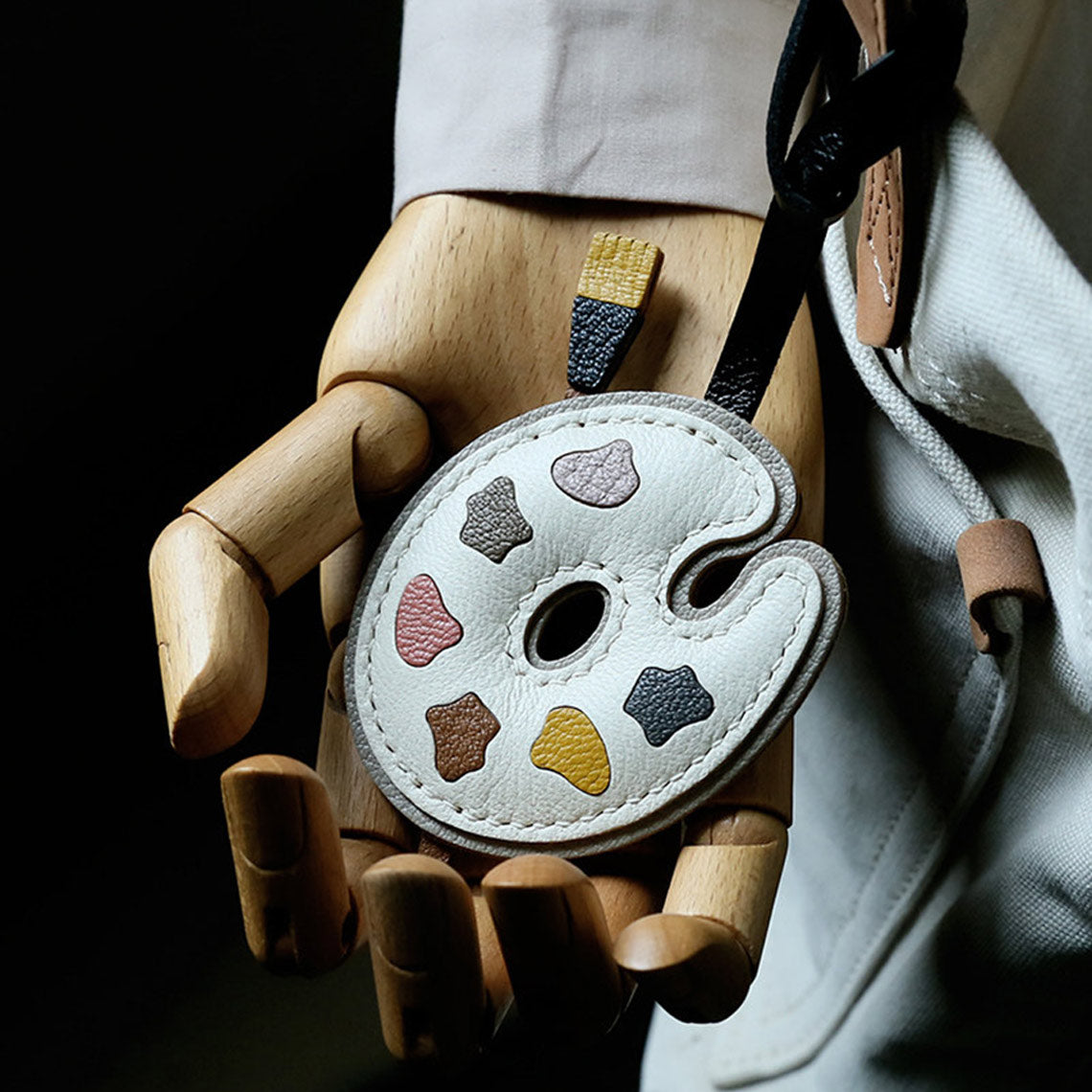 Leather keychain with color swatches held by a wooden hand