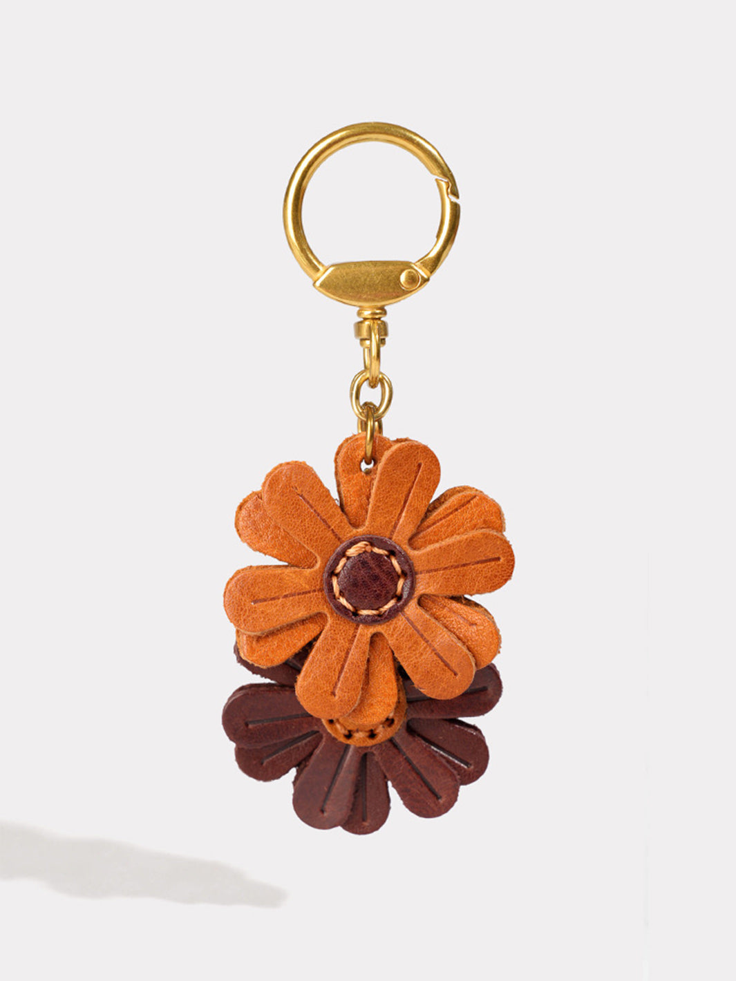 A leather keychain charm with a gold-tone ring, featuring two small flowers