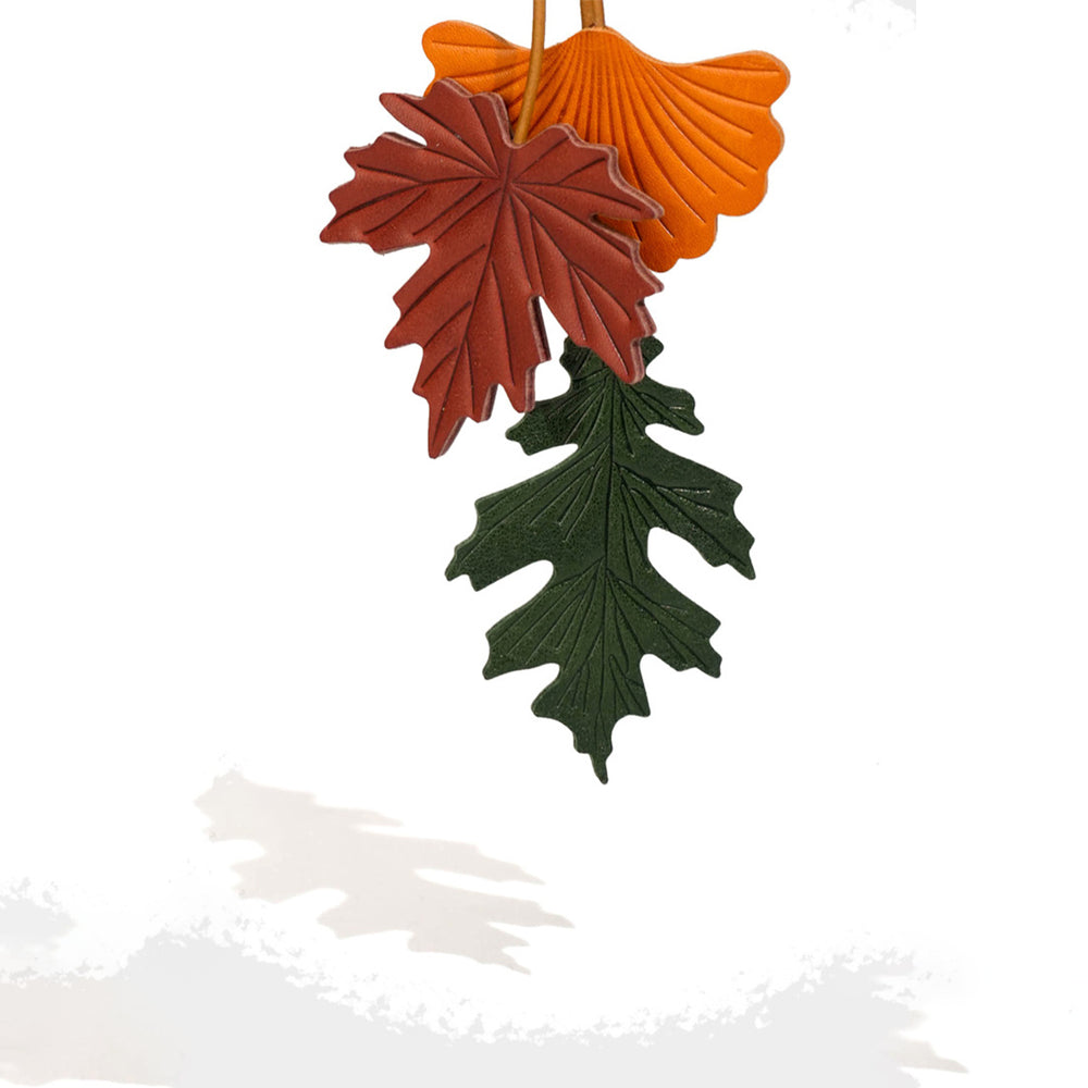 Three leaf-shaped ornaments in red, green, and orange on a white background