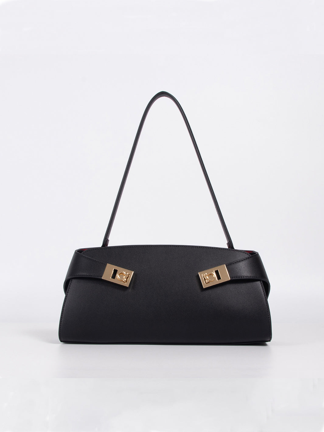 A black leather handbag with a structured rectangular shape, a single shoulder strap, and two prominent gold-tone metal lock hardware details on the front flap, set against a plain white studio background.