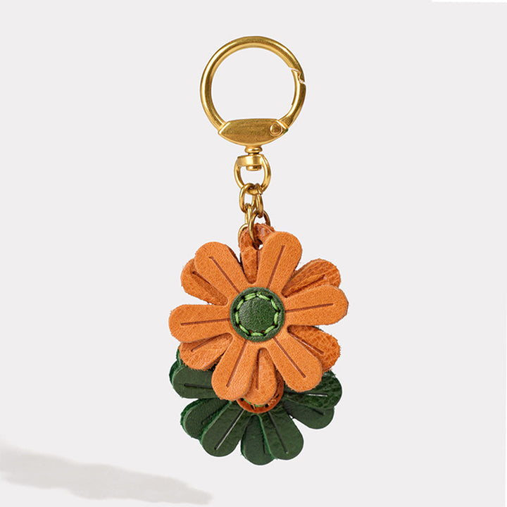 A handmade leather flower keychain charm with orange  and green petals
