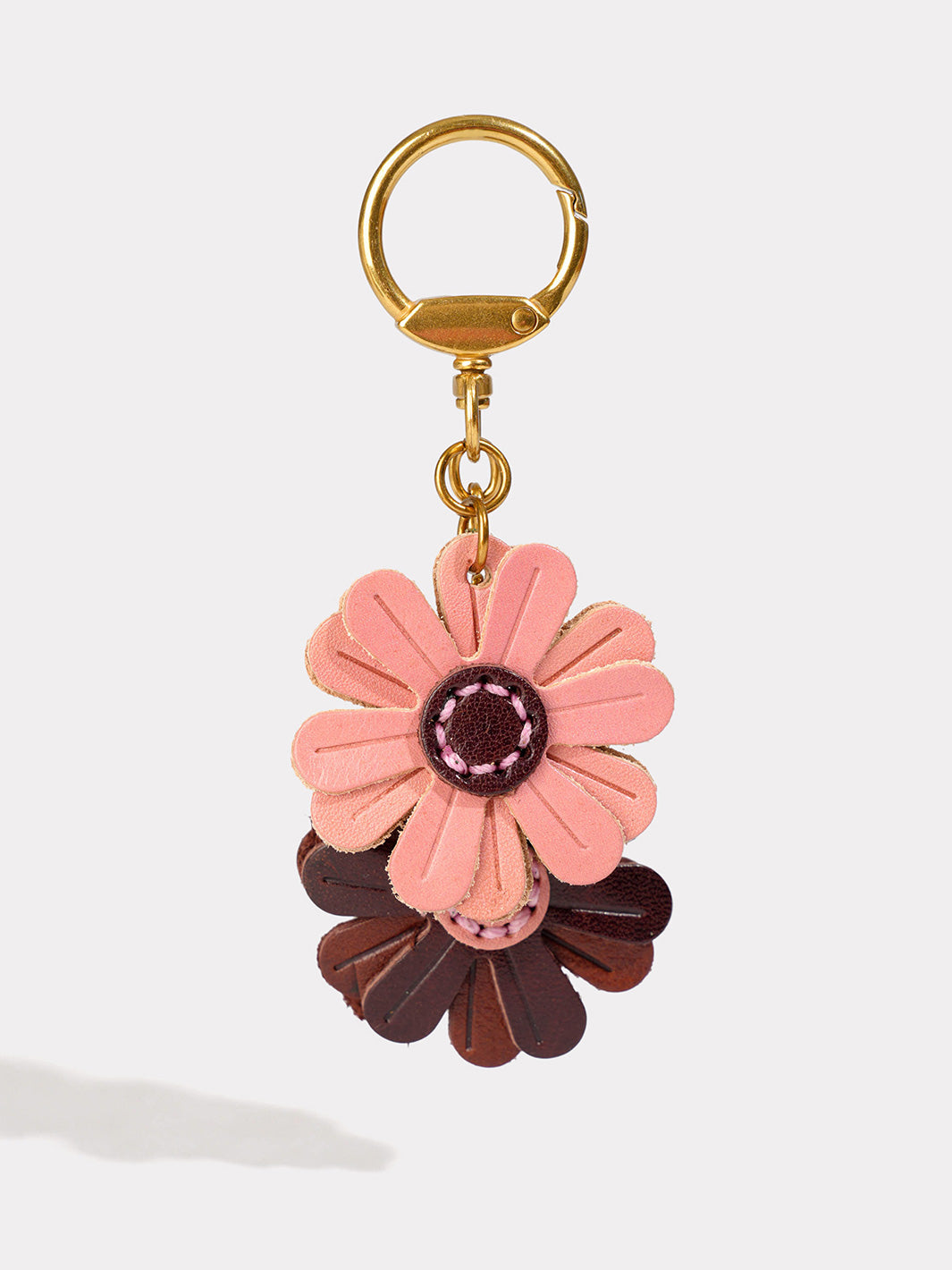 A floral leather keychain charm featuring a pink flower with a dark brown flower