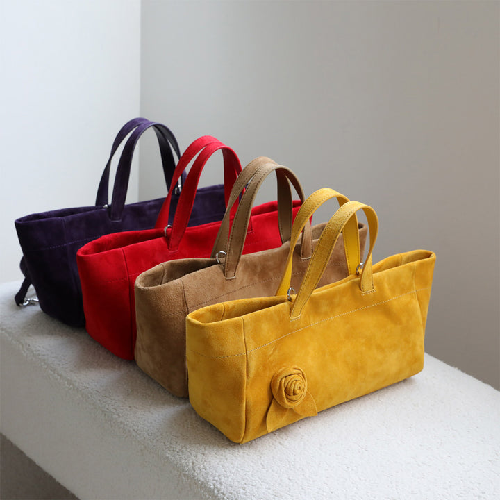 Four suede tote bags in dark purple, red, tan, and mustard yellow