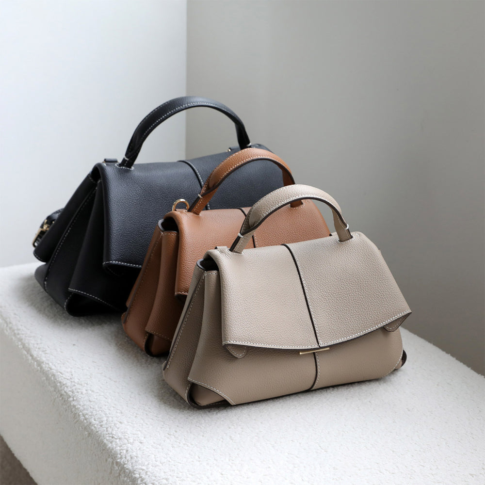 Three leather handbags in black, brown, and beige on a light surface with a neutral background